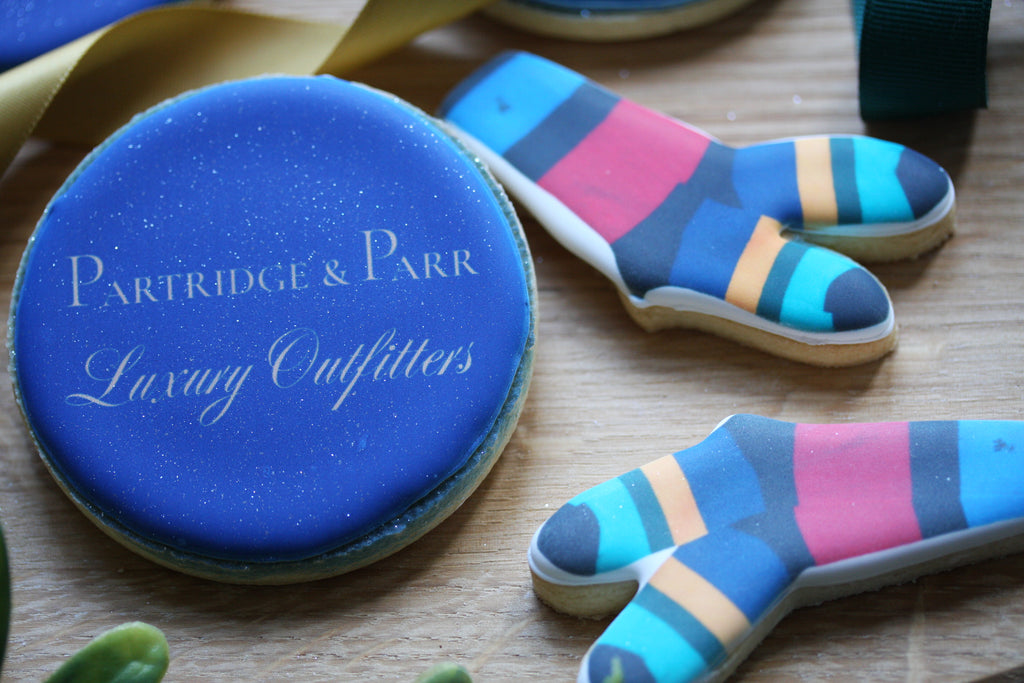 Cookie cutters shaped like socks with colorful stripes on a wooden surface, branded 'Partridge & Parr'.