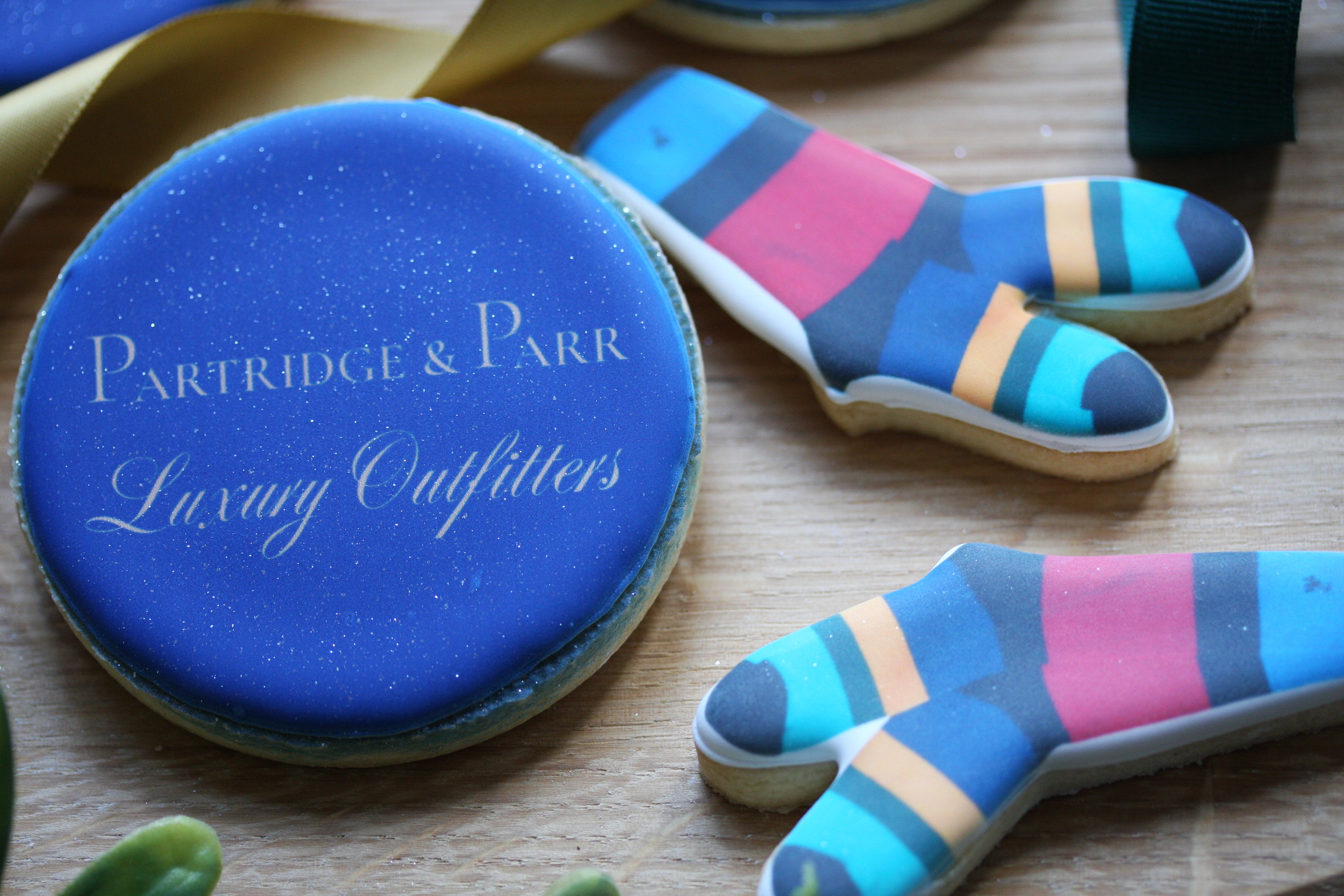 Cookie cutters shaped like socks with colorful stripes on a wooden surface, branded 'Partridge & Parr'.