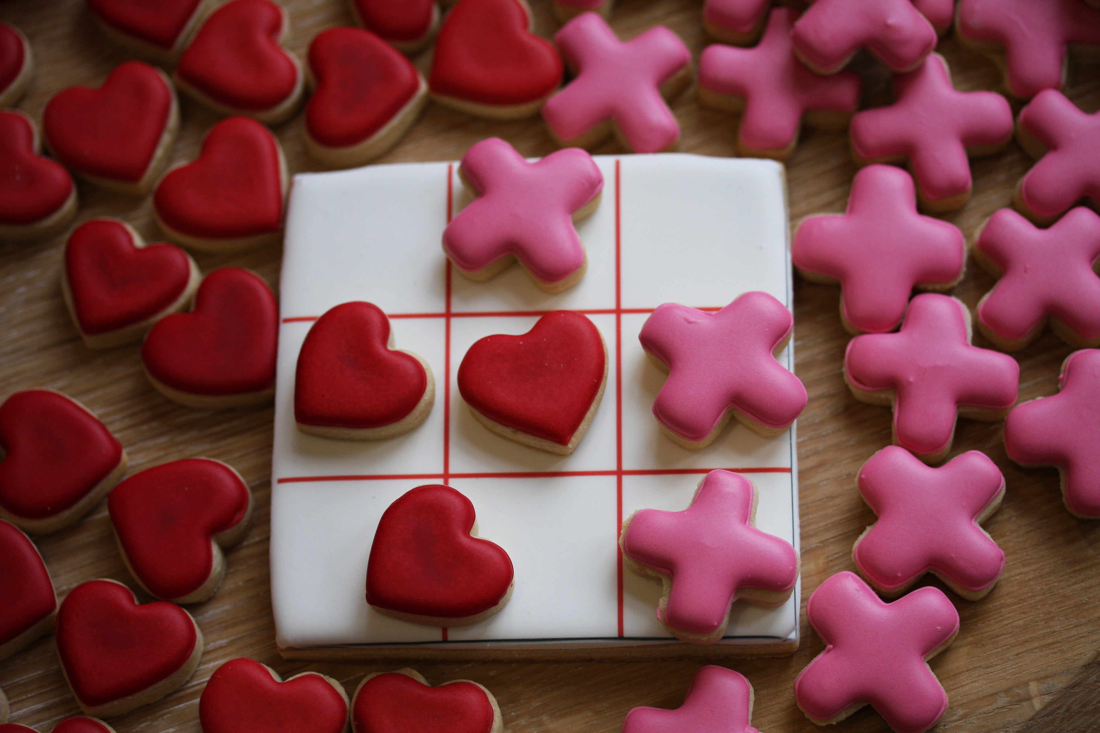Decorative cookies shaped like hearts and crosses on a wooden surface.