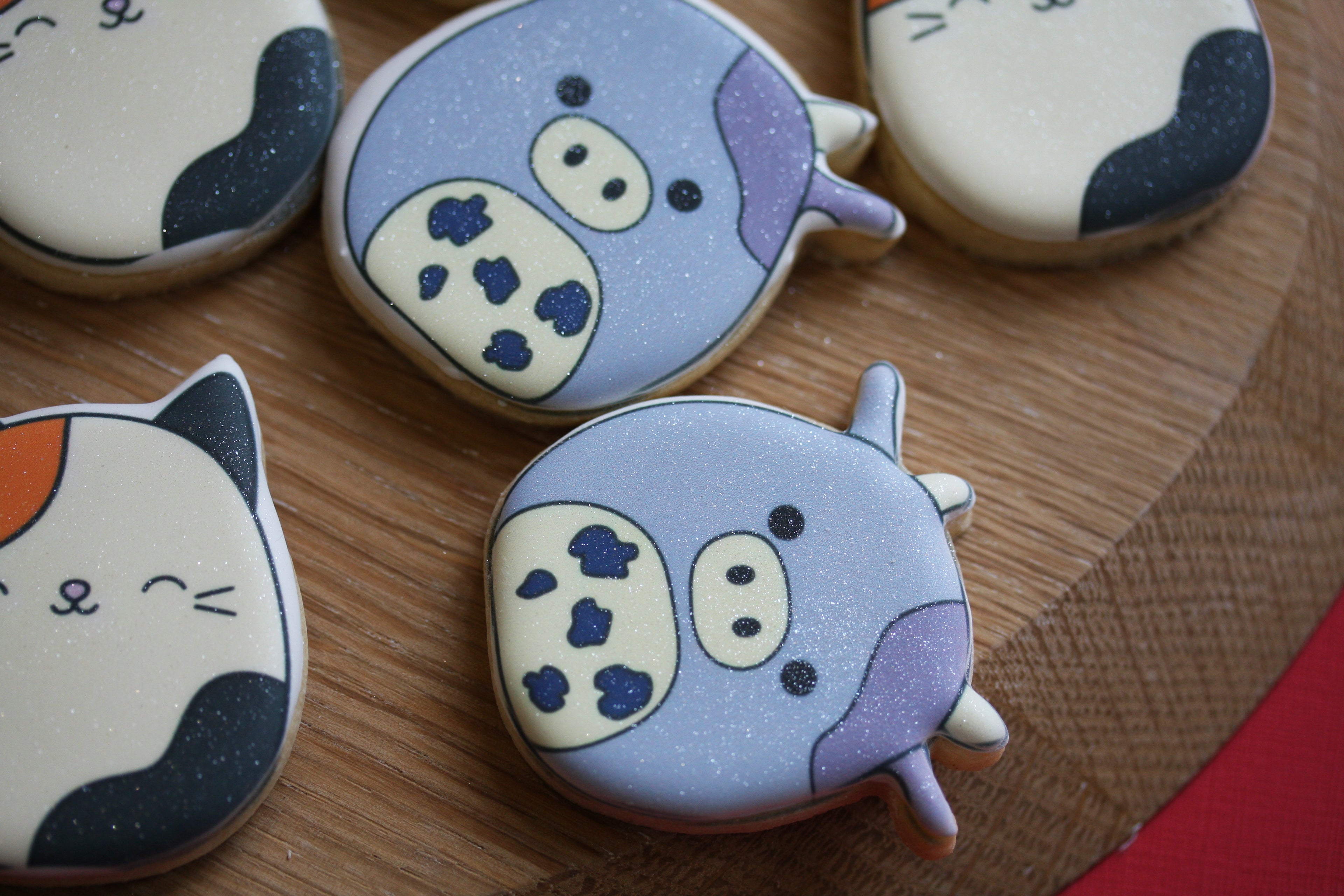 Decorative cookies shaped like cartoon cats on a wooden surface