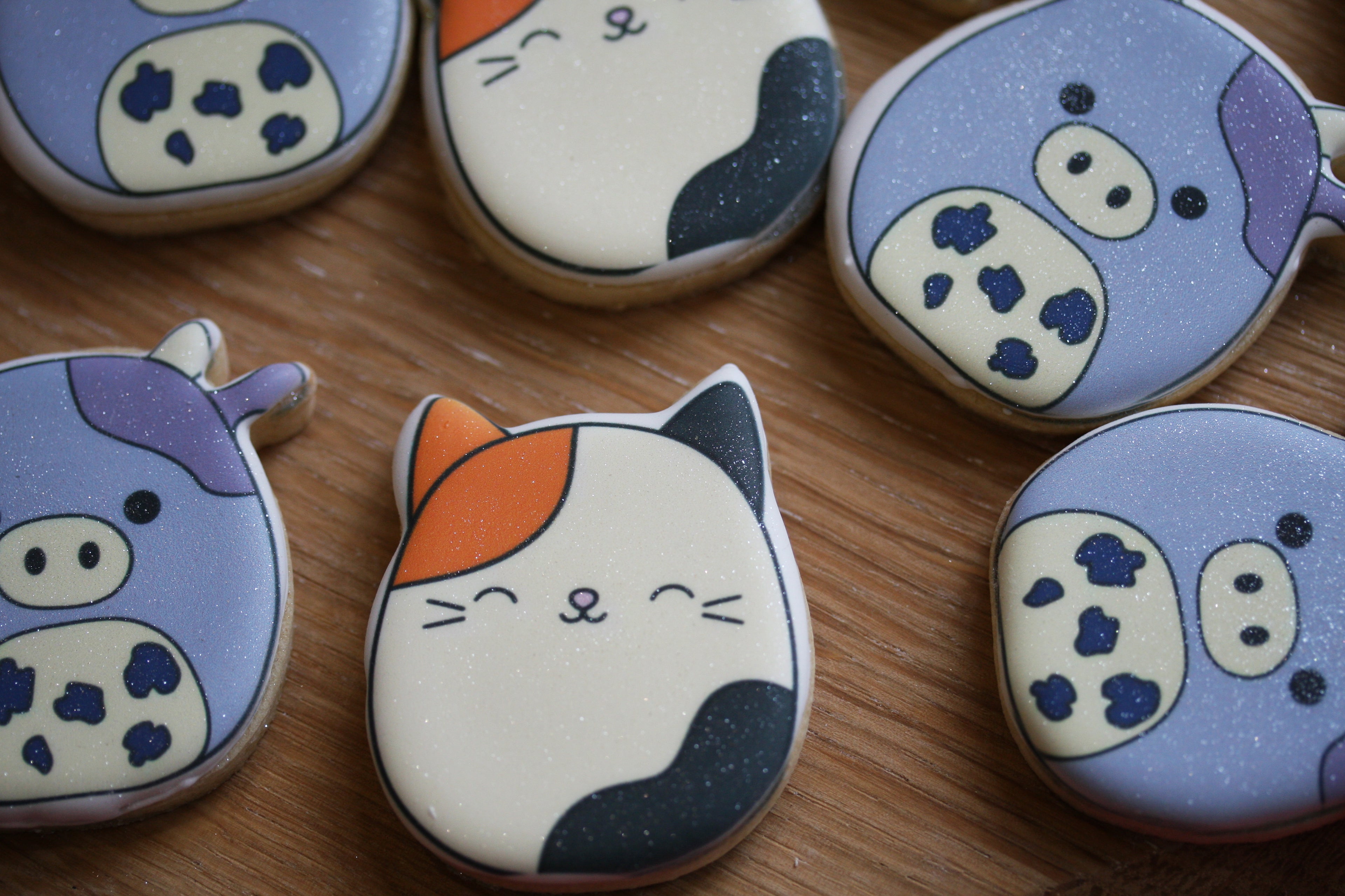Cat-shaped cookies with blue and white designs on a wooden surface